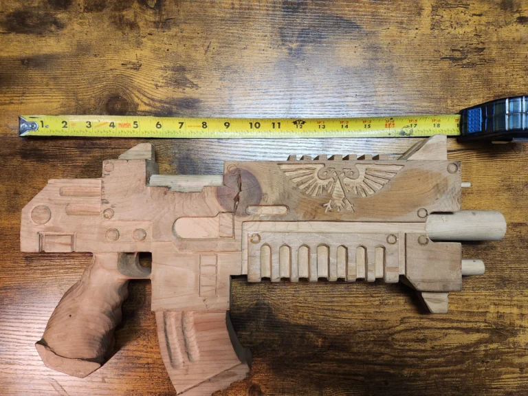 Hand carved wooden Warhammer 40k bolter with measuring tape showing 19inches
